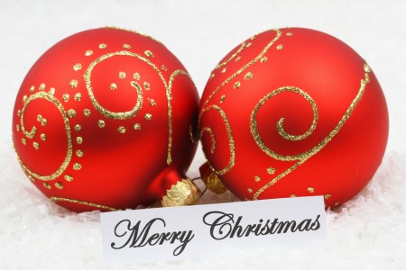 Merry Christmas card with red baubles on snowy surface